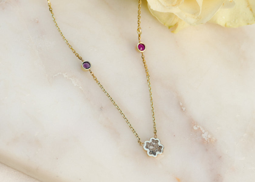 Het as van haar moeder verwerkt in een geel goud collier met handgravure en geboortestenen
