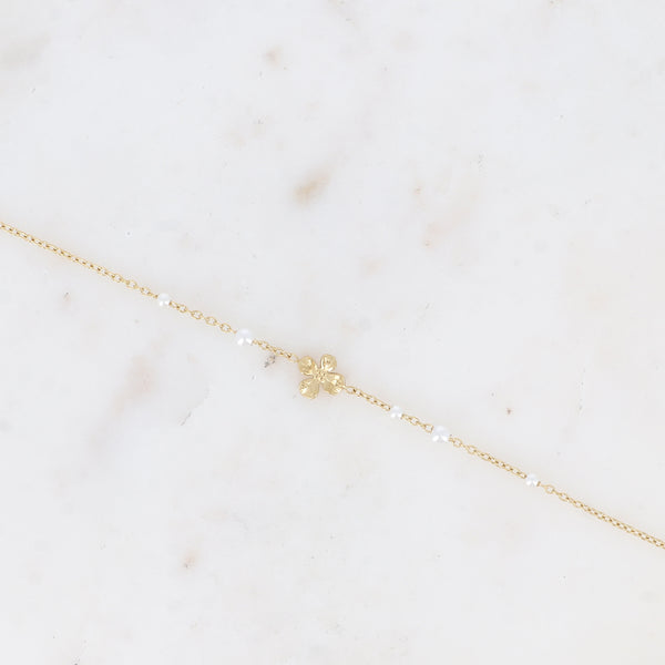 fijn goudkleurig armbandje met bloem en witte pareltjes | stainless steel