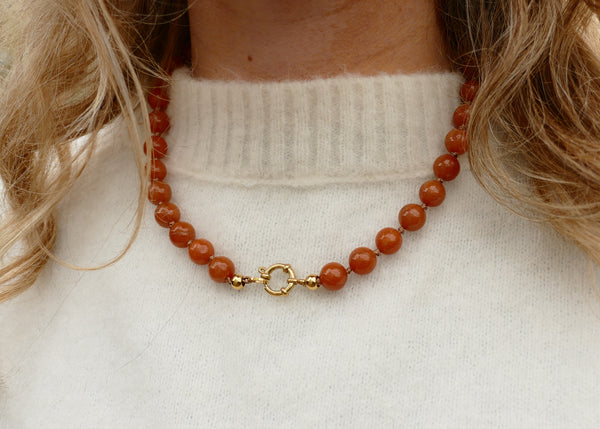 handgeknoopt collier van oranje aventurijn mineralen met goudkleurig groot slot